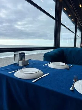 A dining table set for two overlooking the sea on a cloudy day. concept of fi Foto stock