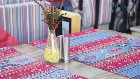 Dining table setup with colorful tablecloth and decor elements Stock Footage 304479509