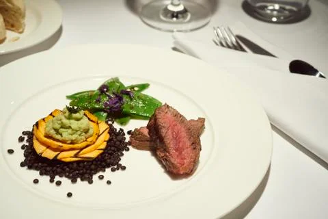 Dinner with beef on a pure white dinner plate with bread, water and wine Stock Photos