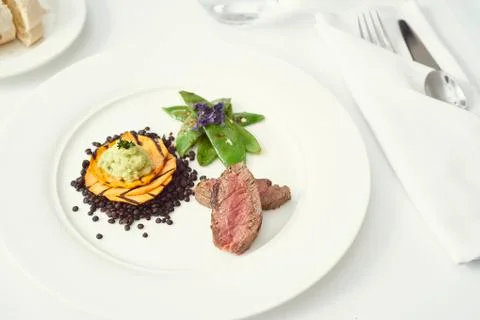 Dinner with beef on a pure white dinner plate with bread, water and wine Stock Photos