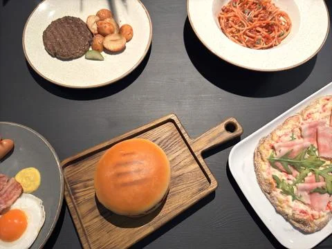 Dinner on a gray table of pizza burger pasta scrambled eggs top view Stock Photos