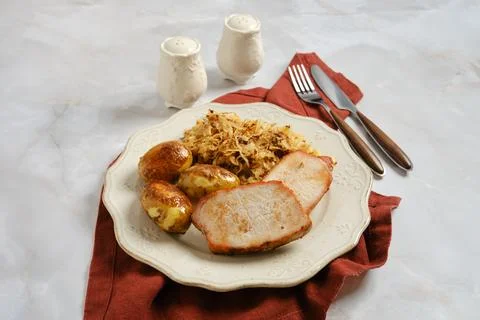 Dinner plate with pork chops, roasted potatoes, and fried sauerkraut on tab.. Foto stock