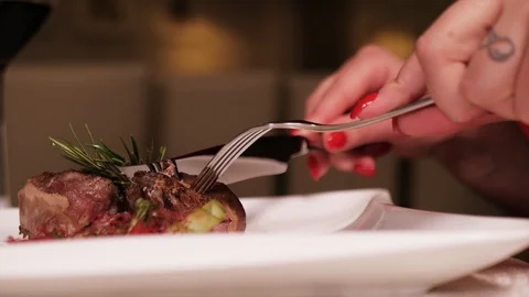 Dinner in the restaurant. Women's hands cut the meat with a knife and fork Stock Footage 108719690