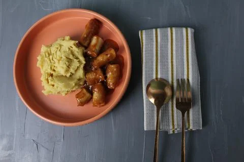 Dinner serving: mashed potatoes and sausages in sauce in a beautiful plate .. Stock Photos