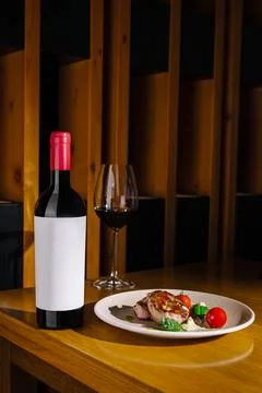 Dinner setting with wine and plated food on a wooden table Stock Photos
