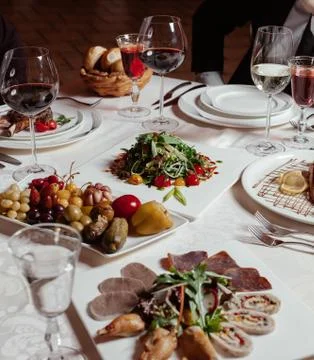 Dinner setup with red wine, pickle plate, meat plate, fresh salad Stock Photos