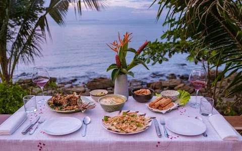 Dinner table looking out over ocean with Thai food, dinner during sunset Fotos Stock
