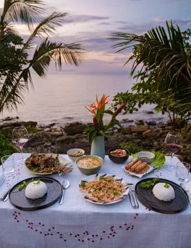 Dinner table looking out over ocean with Thai food, dinner during sunset Fotos Stock