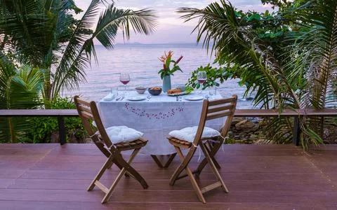 Dinner table looking out over ocean with Thai food, dinner during sunset Fotos Stock