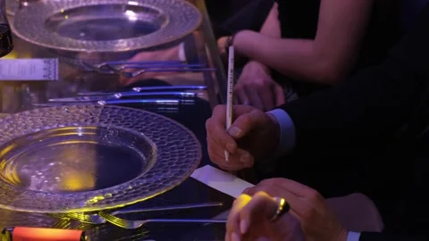 At the dinner table a man writes on a small piece of paper Stock Footage 167510339