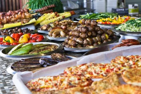 Dinner table with meat grill, roast new potatoes, vegetables, salads, sauces, Stock Photos