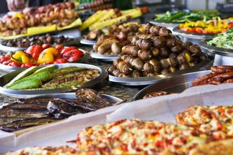 Dinner table with meat grill, roast new potatoes, vegetables, salads, sauces, Stock Photos