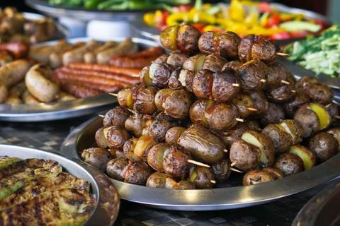 Dinner table with meat grill, roast new potatoes, vegetables, salads, sauces, Foto stock