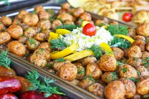 Dinner table with meat grill, roast new potatoes, vegetables, salads, sauces, Stock Photos