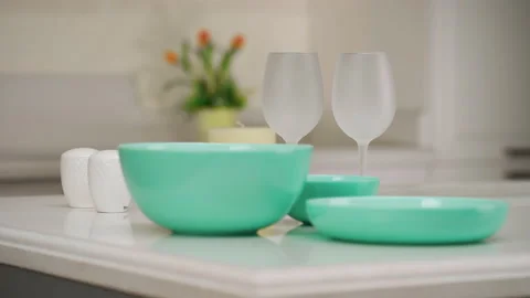 Dinner table setting. Green plates and wine glasses stand on the table. Set of 库存影片 173540720