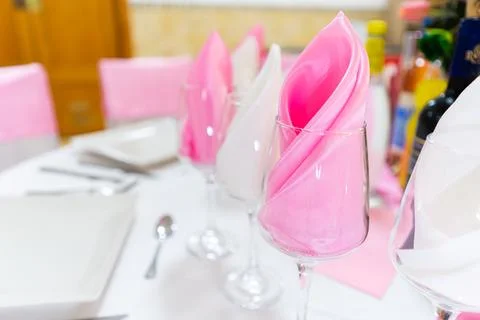 Dinner table setting with plates napkins glasses on pink satin runner caterin Stock Photos
