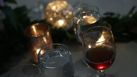 Dinner table with wine and water glasses illuminated by candle light Stock Footage 139852265