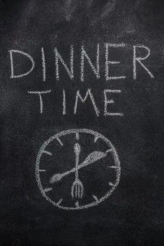 Dinner time text with clock on black chalkboard Stock Photos