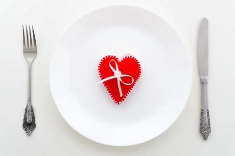 Dinner white table top view with a dish, cutlery and red felt heart. Top view Stock Photos
