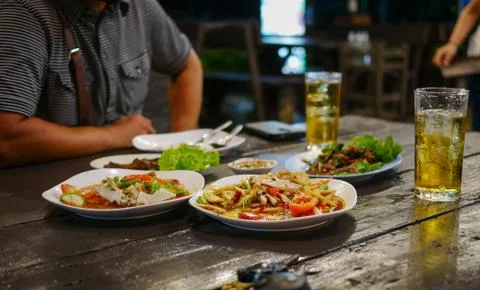 Dinning table in restaurant including Thai foodwith man sit in the opposite Stock Photos