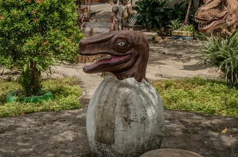 A dinosaur egg is sitting on the ground in front of a tree Stock-Fotos