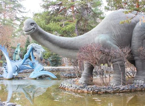 Dinosaur figure statues. model dinosaur stands in front of a mossy rock. Close Stock Photos