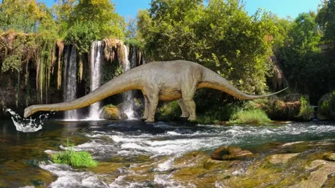 A dinosaur stands by a waterfall and drinks water - real time - loop Stock-Footage 145721282
