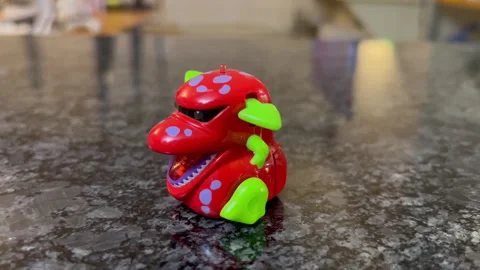 A dinosaur toy walking on the marble table with a reflection in the kitchen Stock Footage 243249902