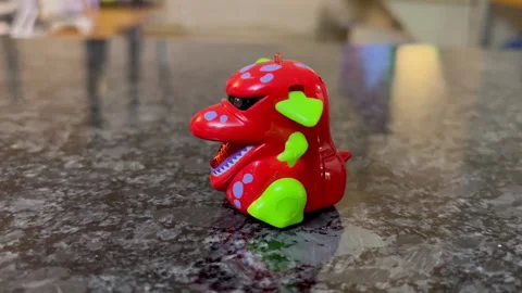 A dinosaur toy walking on the marble table with a reflection in the kitchen Stock Footage 243340151
