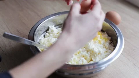 Dip the egg into the flour with cottage cheese and stir for the cheesecake Stock Footage 219615340