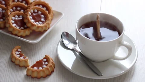 Dip tea bag into white ceramic cup and homemade cookies on plate close up Stock Footage 150109792