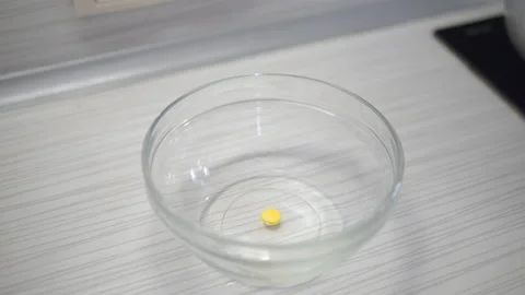 Dip a yellow tablet into a plate of liquid. Easter egg paint Stock Footage 153908761