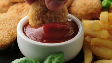 Dipped, crispy chicken nuggets in ketchup Stock Footage 153434016