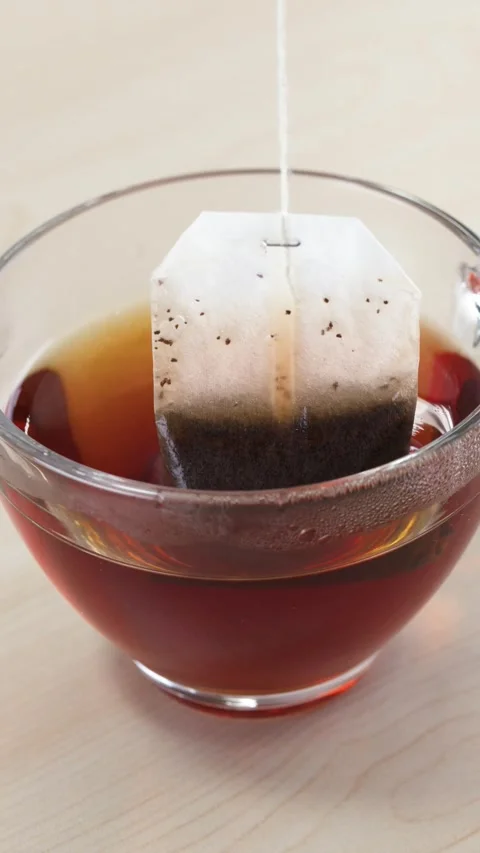 Dipping and Steeping a Tea Bag in Glass Cup Stock Footage 346013184