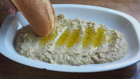 Dipping bread in a bowl of hummus and olive oil Stock Footage 339755309