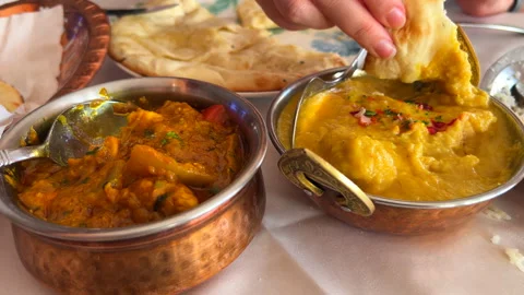 Dipping cheese naan bread in Korma chicken dish sauce and Handi chicken dish Stock Footage 296580241