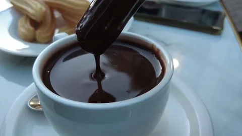 Dipping a churro into a cup of hot chocolate Stock Footage 231104145