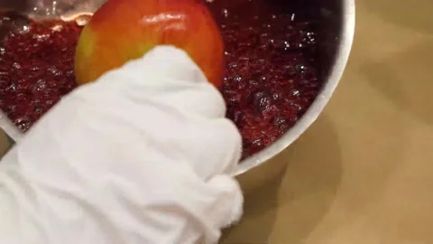 Dipping a Fresh Red Apple into Boiling Red Candy Sugar Coating 動画素材 345292589