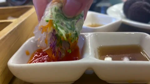 Dipping fresh spring roll into rich sauce enhances the flavor. Sauces add Stock Footage 301517484