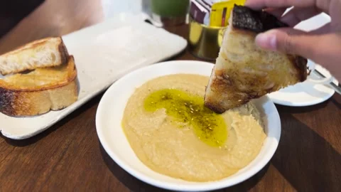 Dipping Fresh Warm Sourdough Slice into Hummus Dip Stock Footage 270109732