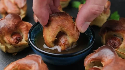 Dipping Mini Toad in the hole in gravy. Baked sausages in Yorkshire pudding Stock Footage 256012269