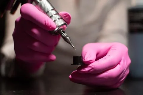 Dipping a needle into a paint for a tattoo machine Stock Photos