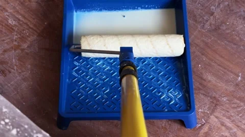 Dipping paint roller attached to extension pole into liquid primer tray Stock Footage 340403940