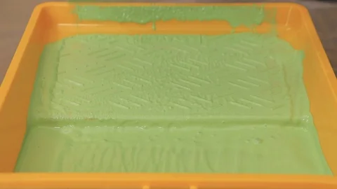 Dipping a paint roller into the paint tray with green paint Stock Footage 122212422
