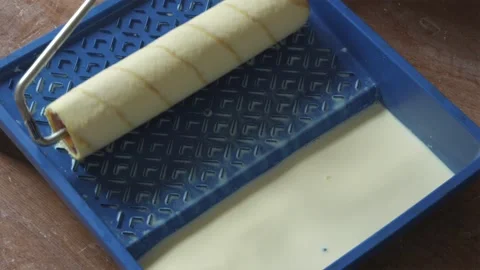 Dipping paint roller into primer tray and removing excess liquid Stock Footage 340404005