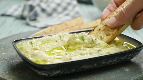 Dipping a piece of bread in courgette and white bean dip. Stock Footage 247895771