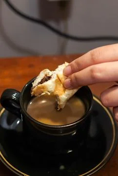Dipping a piece of bread into a cup of coffee 스톡 사진
