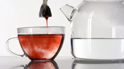 Dipping red tea bag in a transparent mug with hot water on white background Stock Footage 144431472