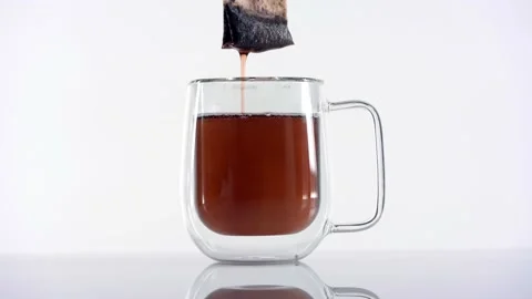 Dipping red tea bag in a transparent mug with hot water on white background Video stock 144431584