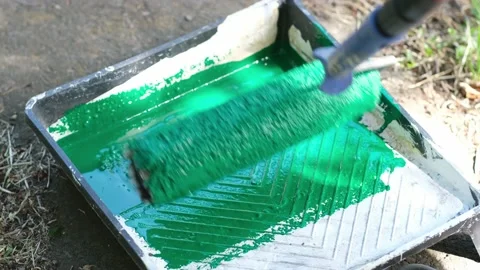 Dipping roller into plastic tray with green paint outdoors. House renovation Stock Footage 202239617